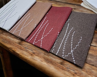 Manteles individuales bordados de estilo rústico: tela con aspecto de lino en tonos crema, rojo y marrón con estampado de flores silvestres.