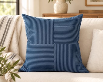 May include: A square throw pillow featuring a patchwork design of dark blue fabric with white pinstripes. The pattern alternates between vertical and horizontal stripe orientations in four distinct quadrants, creating a grid-like visual effect.