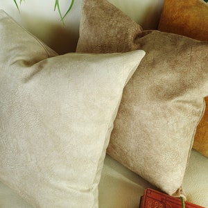 May include: Three decorative throw pillows in various shades of brown. The pillows are made of a soft, textured fabric.