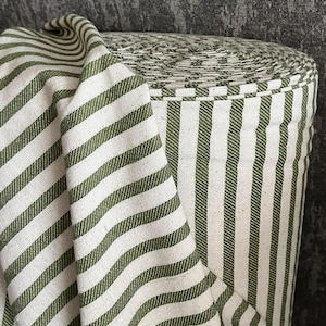 May include: A roll of white and green striped fabric. The fabric has a subtle texture and is perfect for sewing projects.