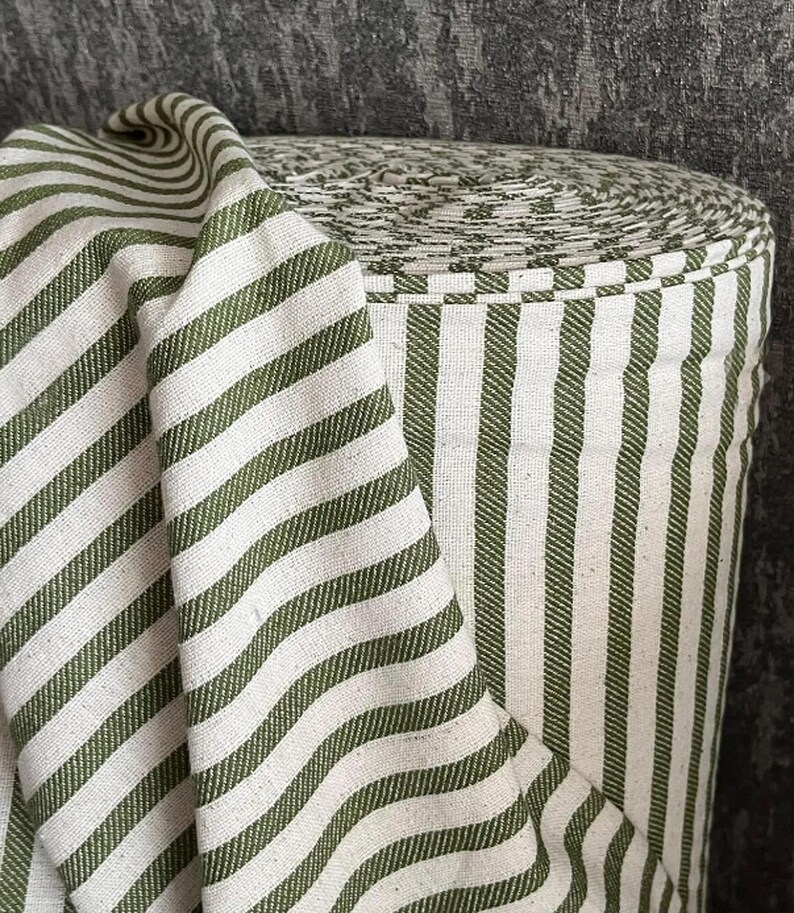 May include: A roll of white and green striped fabric. The fabric has a subtle texture and is perfect for sewing projects.
