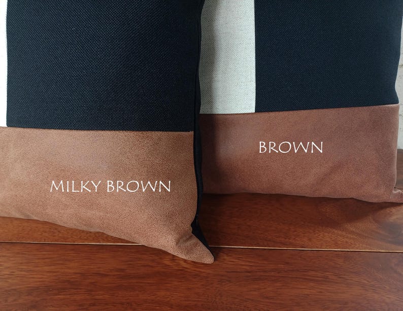 May include: Two decorative throw pillows with a color block design. The top portion of each pillow is navy blue, with a white stripe on one. The bottom section is a brown suede-like material. One pillow has the text "Milky Brown" and the other has "Brown".