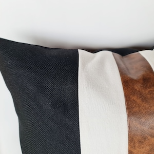 May include: A black, white and brown striped cushion with a textured fabric.