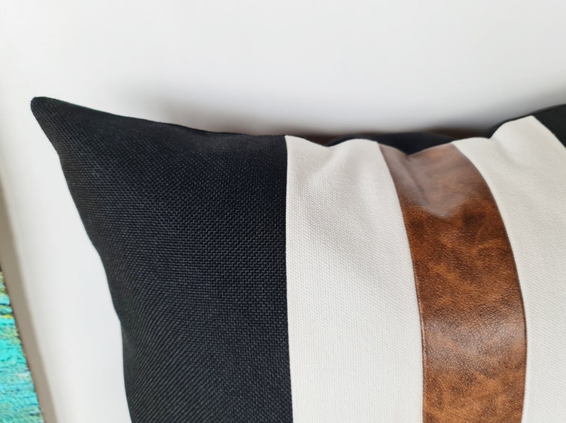 May include: A black, white and brown striped cushion with a textured fabric.