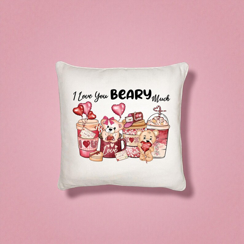 May include: White square pillow with a Valentine's Day theme. The pillow features the phrase "I Love You BEARY Much" above illustrations of teddy bears and coffee cups with heart-shaped balloons and the word "Love".
