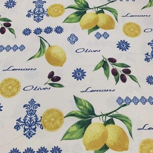 May include: White fabric with a repeating pattern of lemons, olives, and blue floral and geometric designs. The words "Lemons" and "Olives" are written in a cursive font. The lemons are yellow, and the olives are purple.