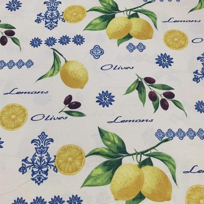 May include: White fabric with a repeating pattern of lemons, olives, and blue floral and geometric designs. The words "Lemons" and "Olives" are written in a cursive font. The lemons are yellow, and the olives are purple.