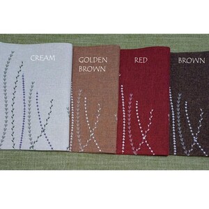May include: Four placemats with embroidered floral designs in cream, golden brown, red, and brown. The placemats are labeled "CREAM", "GOLDEN BROWN", "RED", and "BROWN".