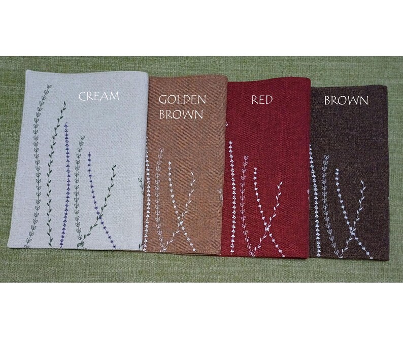 May include: Four placemats with embroidered floral designs in cream, golden brown, red, and brown. The placemats are labeled "CREAM", "GOLDEN BROWN", "RED", and "BROWN".