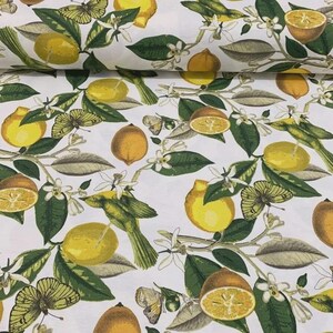 May include: White fabric with a repeating pattern of yellow lemons, orange halves, green leaves, white blossoms, and butterflies. The design includes a bird perched on a branch with lemons.