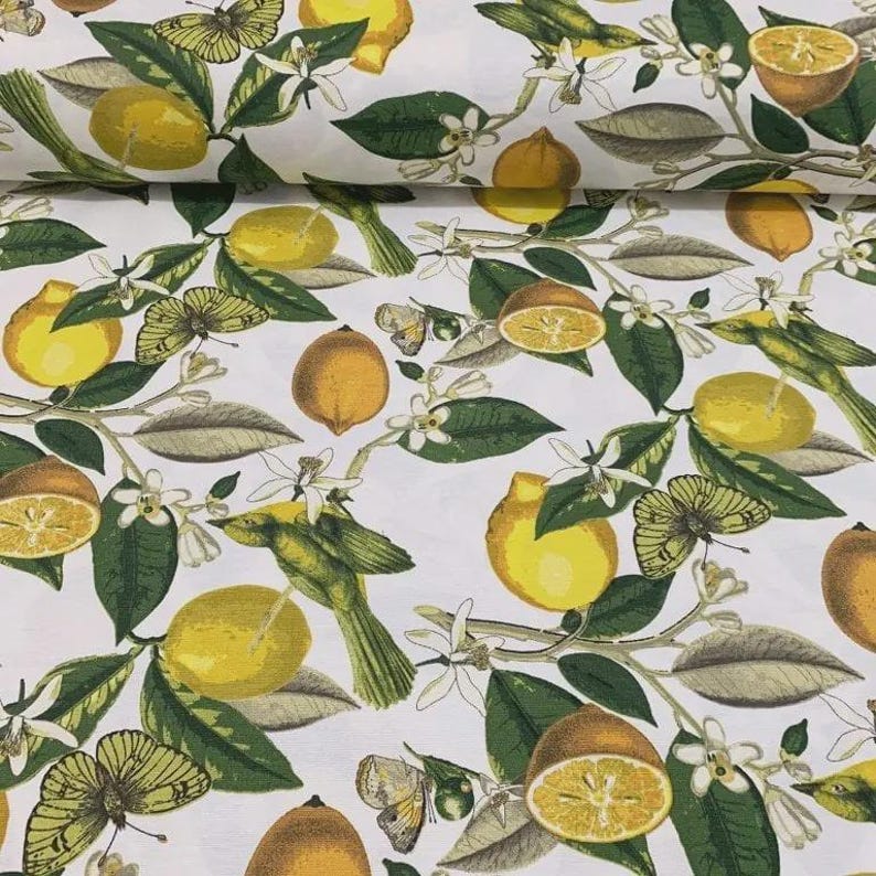 May include: White fabric with a repeating pattern of yellow lemons, orange halves, green leaves, white blossoms, and butterflies. The design includes a bird perched on a branch with lemons.