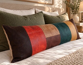 May include: A long rectangular lumbar pillow featuring a patchwork design of faux leather panels in dark brown, bright red, tan, dark teal, and mustard yellow. The pillow has a visible textured surface and is stitched together in vertical and horizontal segments.