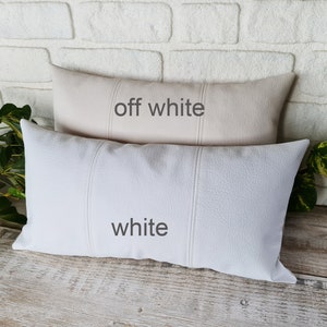 May include: Two decorative throw pillows, one off-white and one white. Both pillows have a textured fabric and are rectangular in shape.