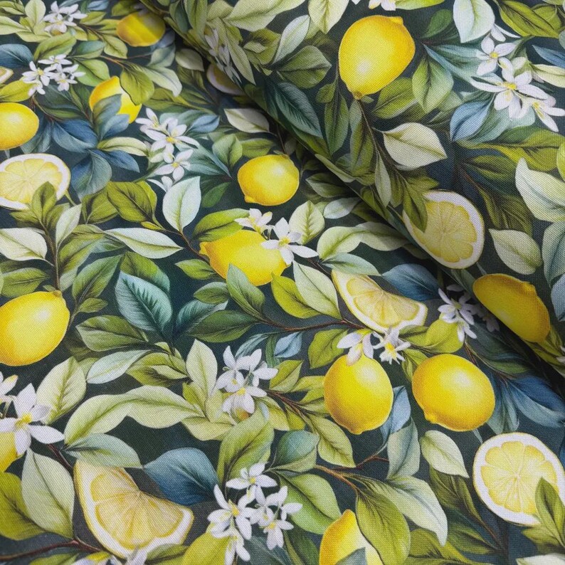 May include: Fabric with a lemon and floral pattern. The design features bright yellow lemons, white blossoms, and green leaves against a dark green background. The fabric is likely cotton or a similar material, suitable for various sewing projects.