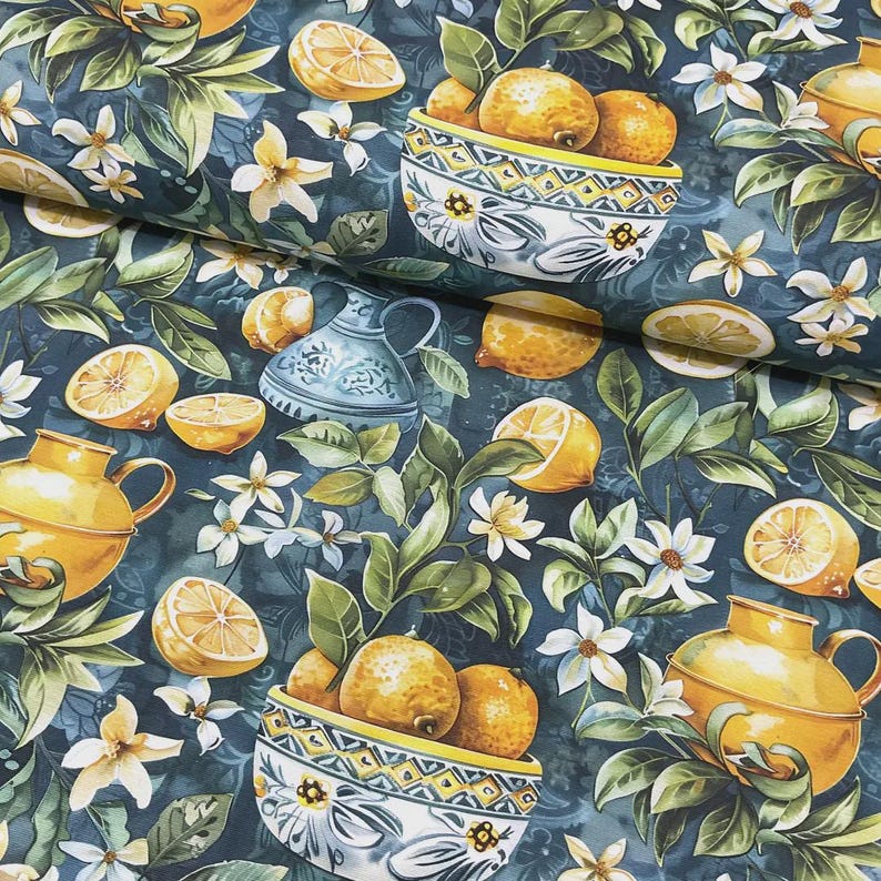 May include: A fabric with a dark teal background featuring a pattern of lemons, white flowers, and green leaves. Yellow pitchers and bowls filled with lemons are also present. The lemons are whole and sliced, creating a vibrant, summery design.