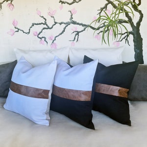 Puede incluir: Cuatro almohadas decorativas con detalles en cuero marr&oacute;n. Dos almohadas son blancas con detalles en cuero marr&oacute;n y dos almohadas son negras con detalles en cuero marr&oacute;n.