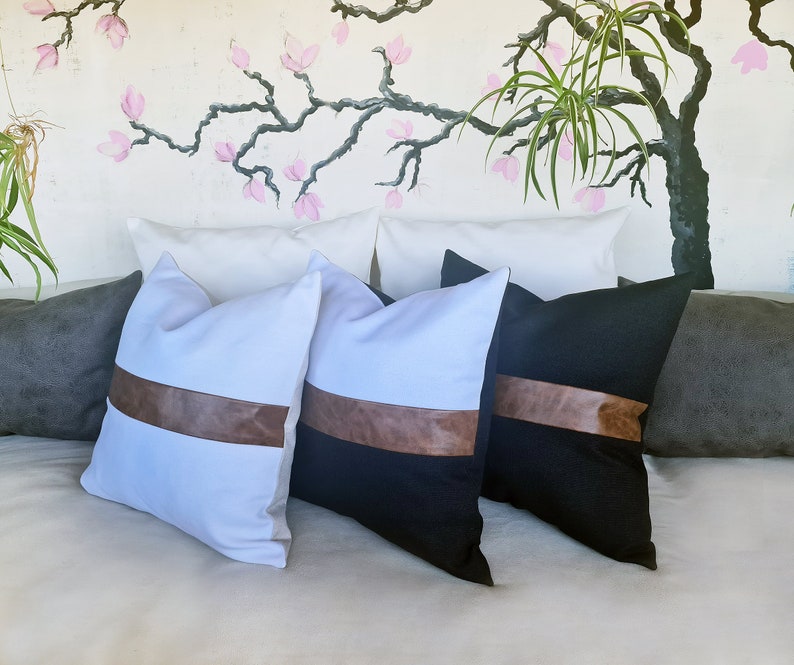 Puede incluir: Cuatro almohadas decorativas con detalles en cuero marr&oacute;n. Dos almohadas son blancas con detalles en cuero marr&oacute;n y dos almohadas son negras con detalles en cuero marr&oacute;n.