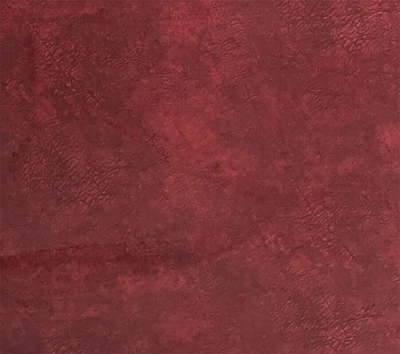May include: A close-up of a textured, burgundy-colored surface. The surface has a mottled appearance with variations in tone, creating a sense of depth and visual interest. The overall effect is rich and luxurious.
