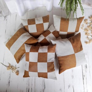 May include: Five decorative throw pillows with a checkered pattern in brown and white. The pillows are made of a soft, textured fabric.