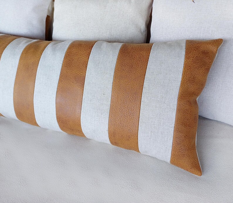 May include: A long, rectangular throw pillow with brown and white stripes. The pillow is made of a soft, textured fabric and has a subtle sheen.