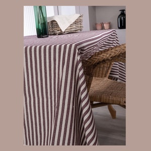 May include: A striped tablecloth in brown and white with a wicker chair in the background.