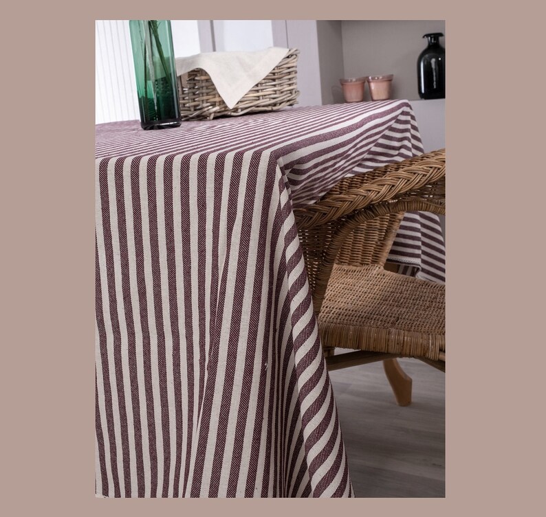 May include: A striped tablecloth in brown and white with a wicker chair in the background.