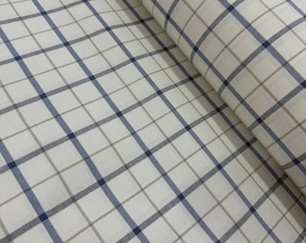 May include: A roll of woven fabric featuring a grid pattern with intersecting lines in navy blue and light gray on an off-white background. The textile displays a consistent checkered design across the surface, showing the texture of the weave.