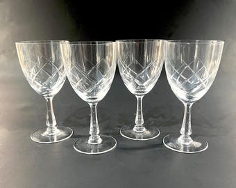 Op de afbeelding: Vier heldere glazen wijnglazen met een diamantpatroon. De glazen hebben een lange, slanke steel en een ronde kom.