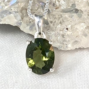 May include: A silver chain necklace with a green oval gemstone pendant.