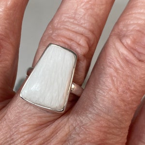 May include: A white ring with a rectangular shaped stone. The stone has a striated pattern.