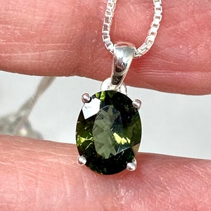 May include: A silver chain necklace with a green oval gemstone pendant.
