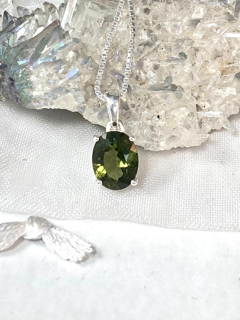 May include: A silver chain necklace with a green oval gemstone pendant.