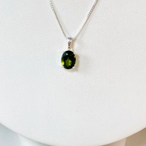 May include: A silver chain necklace with a green oval gemstone pendant.