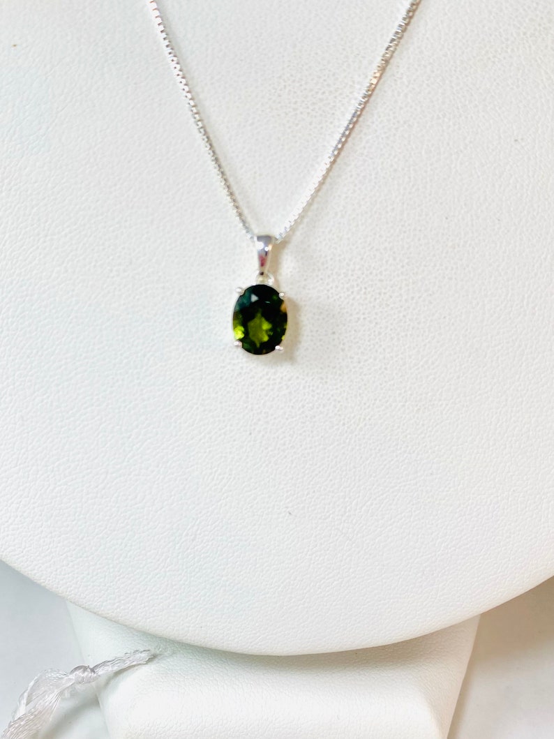 May include: A silver chain necklace with a green oval gemstone pendant.