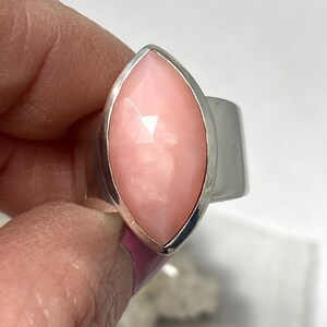 Pode incluir: Um anel de prata com uma gema de opala rosa em forma de marquise.