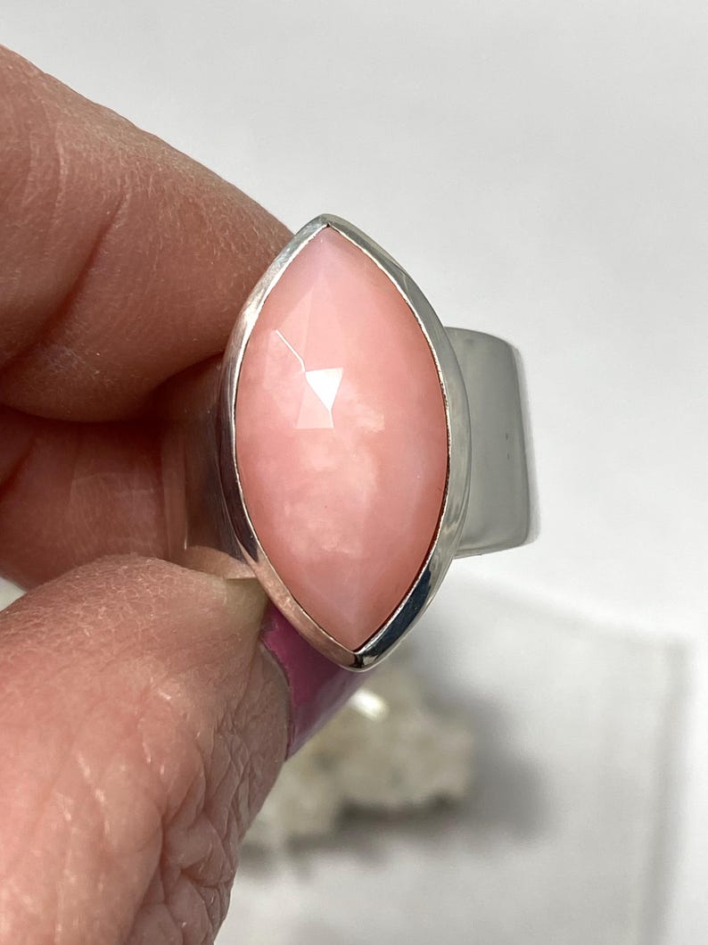 Pode incluir: Um anel de prata com uma gema de opala rosa em forma de marquise.