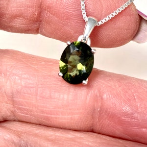 May include: A silver chain necklace with a green oval gemstone pendant.