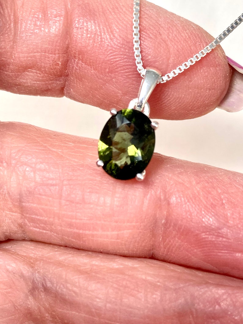 May include: A silver chain necklace with a green oval gemstone pendant.