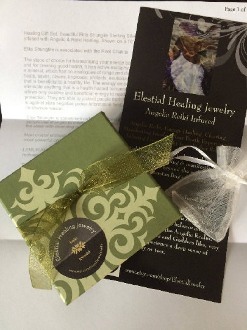 May include: A gift set featuring a green box with a gold ribbon, a small mesh bag, and a black card with the text "Elestial Healing Jewelry, Angelic Reiki Infused." The box has a decorative pattern.