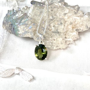 May include: A silver chain necklace with a green oval gemstone pendant.