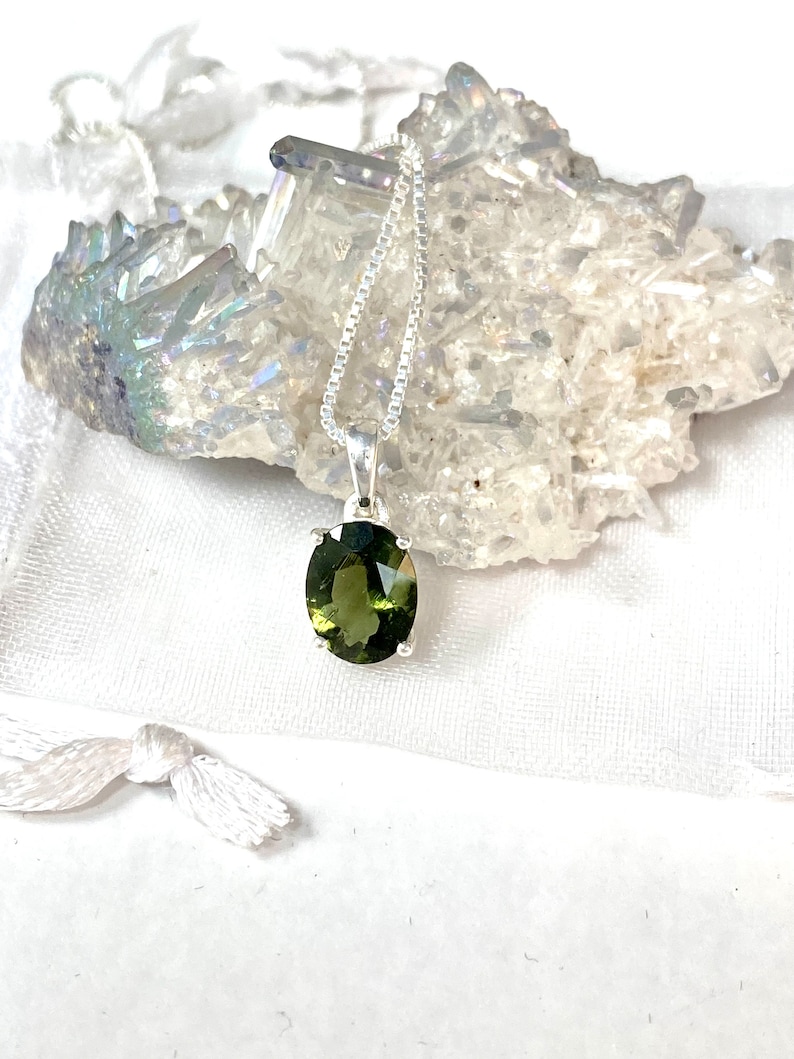 May include: A silver chain necklace with a green oval gemstone pendant.