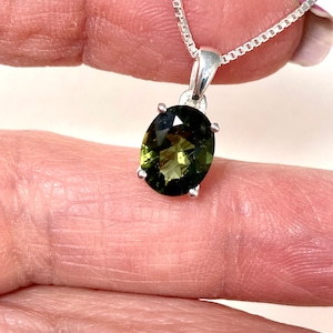 May include: A silver chain necklace with a green oval gemstone pendant.