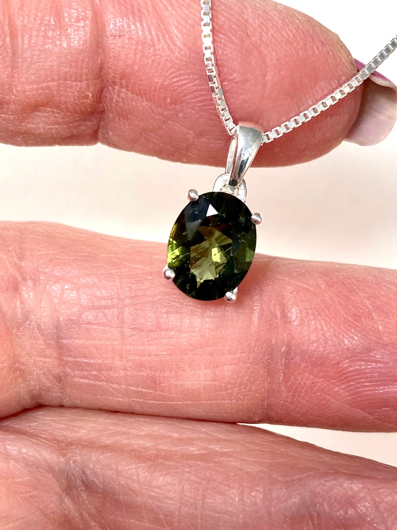 May include: A silver chain necklace with a green oval gemstone pendant.
