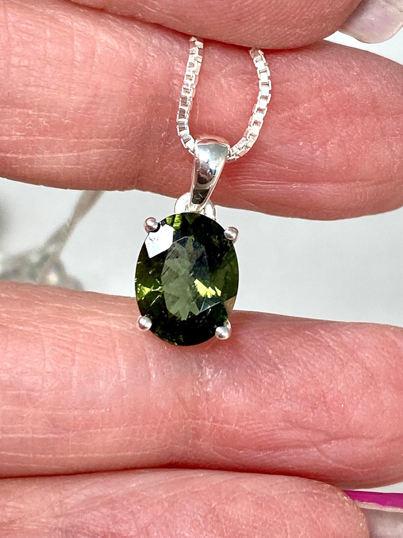 May include: A silver chain necklace with a green oval gemstone pendant.