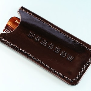 Könnte beinhalten: Ein braunes Lederetui für einen Kamm mit dem eingeprägten Wort "DURGESH" auf der Vorderseite.