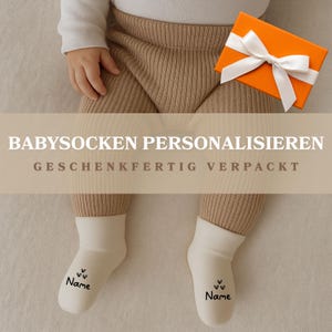 Könnte beinhalten: Ein Baby trägt eine beige gerippte Hose und weiße Socken mit dem Aufdruck "Name". Die Socken haben kleine Herzmotive. Eine orangefarbene Geschenkbox mit weißem Band ist ebenfalls im Bild. Der Text "BABYSOCKEN PERSONALISIEREN" und "GESCHENKFERTIG VERPACKT" ist ebenfalls sichtbar.