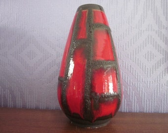 May include: A red and black ceramic vase with a geometric pattern. The vase is tall and narrow, with a rounded bottom and a flared top.