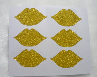 Könnte beinhalten: Sechs goldene Glitzerlippen-Aufkleber auf einem weißen Blatt Papier.