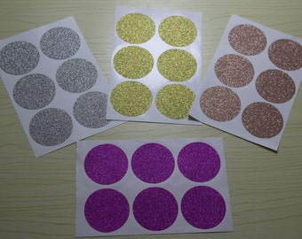 May include: Four sheets of round glitter stickers. Each sheet has 8 stickers in gold, silver, pink, and purple.