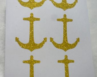 May include: Six gold glitter anchor stickers on a white background. The anchors are in a repeating pattern of three rows of two.